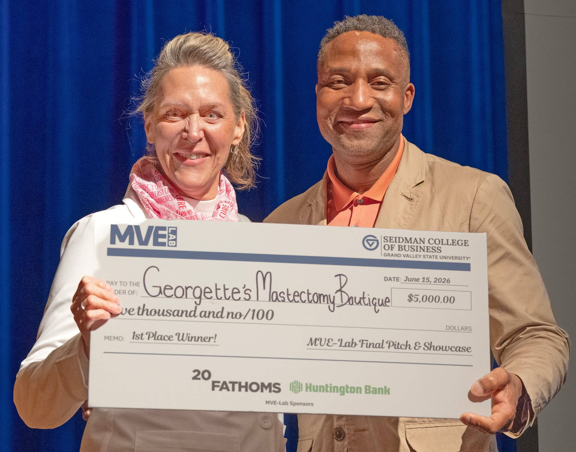 two people holding an oversized check on stage at the Traverse City Opera House